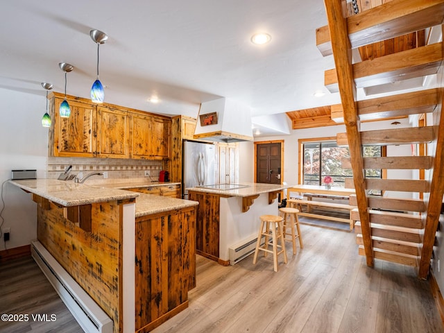 kitchen featuring stainless steel fridge, a baseboard radiator, a peninsula, baseboard heating, and backsplash