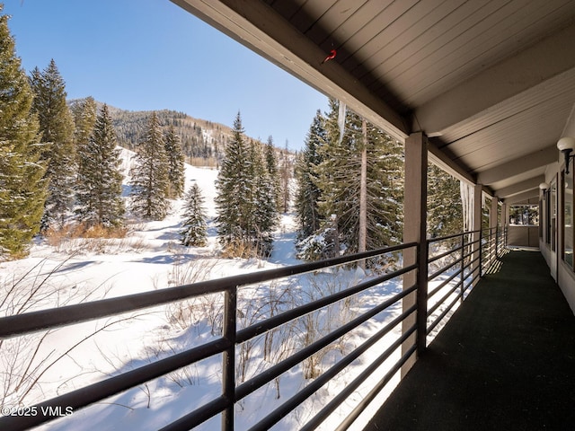 snow covered back of property featuring a wooded view and a mountain view