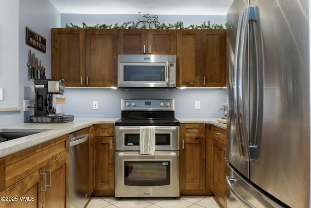 1303 Crazy Horse Cir Unit 1303, Edwards, CO 81632 - kitchen featuring appliances with stainless steel finishes, light tile patterned floors, brown cabinets, and light stone countertops