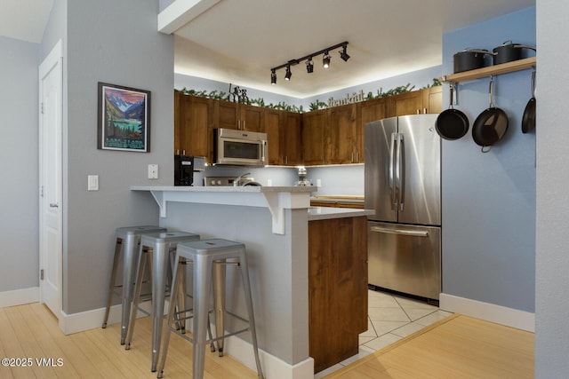 1303 Crazy Horse Cir Unit 1303, Edwards, CO 81632 - kitchen with stainless steel appliances, a peninsula, a breakfast bar area, light countertops, and light wood-type flooring