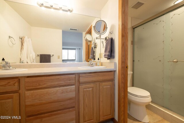 bathroom with a shower with door, vanity, tile patterned floors, and toilet