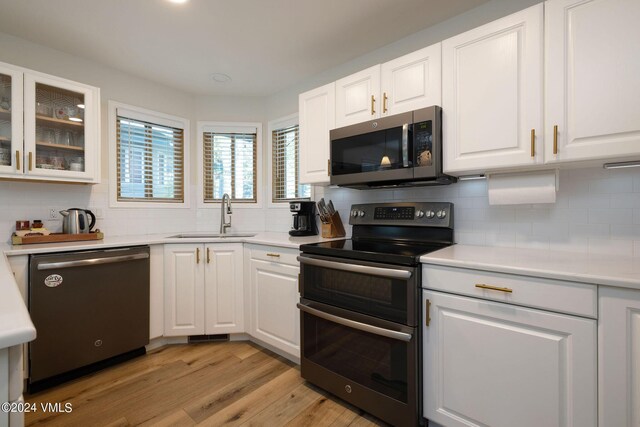 kitchen with sink, appliances with stainless steel finishes, light hardwood / wood-style floors, decorative backsplash, and white cabinets