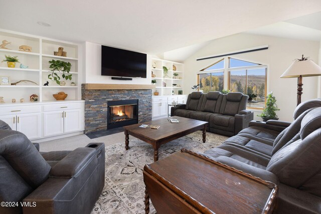 living room featuring lofted ceiling, a stone fireplace, and built in shelves