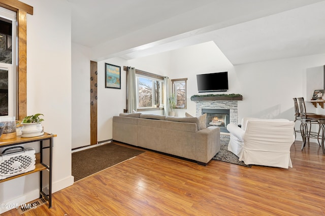 living area featuring a fireplace, wood finished floors, and baseboards