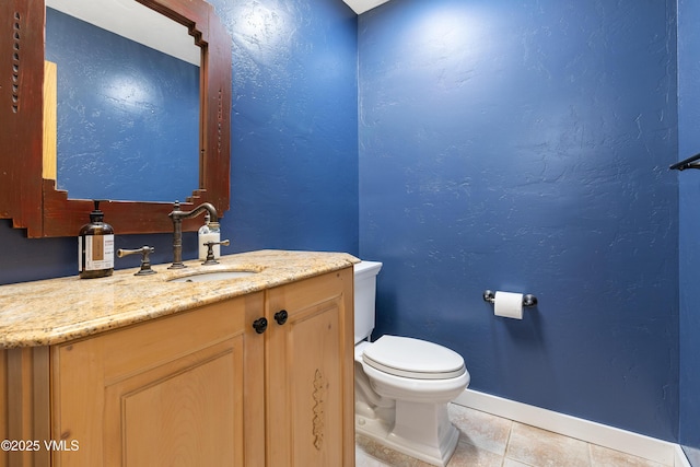 bathroom featuring a textured wall, tile patterned flooring, toilet, vanity, and baseboards