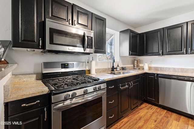 kitchen featuring light wood finished floors, light countertops, appliances with stainless steel finishes, and dark cabinetry