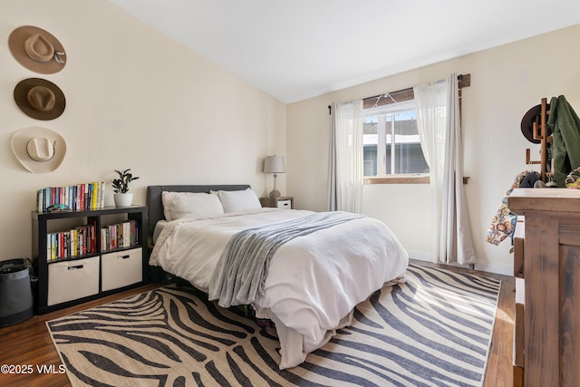 bedroom featuring lofted ceiling, baseboards, and wood finished floors