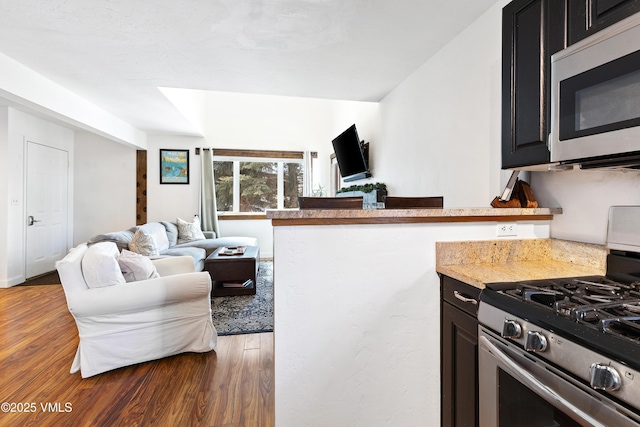 kitchen with open floor plan, wood finished floors, a peninsula, light countertops, and stainless steel appliances