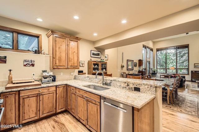 803 June Creek Rd, Edwards, CO 81632 - kitchen with stainless steel dishwasher, a sink, a peninsula, light wood finished floors, and light stone countertops