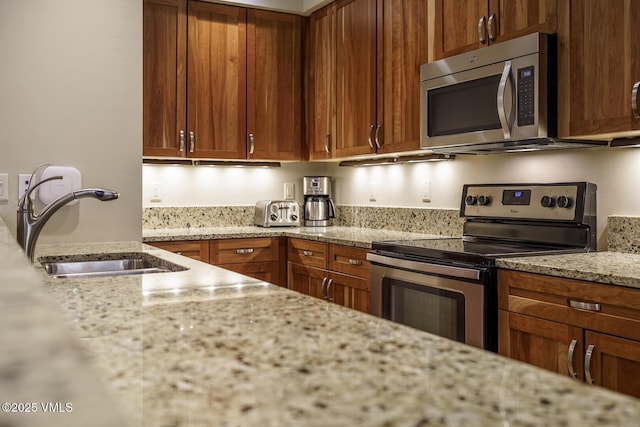 660 Lionshead Pl Unit 9, Vail, CO 81657 - kitchen with stainless steel appliances, a sink, light stone counters, and brown cabinets