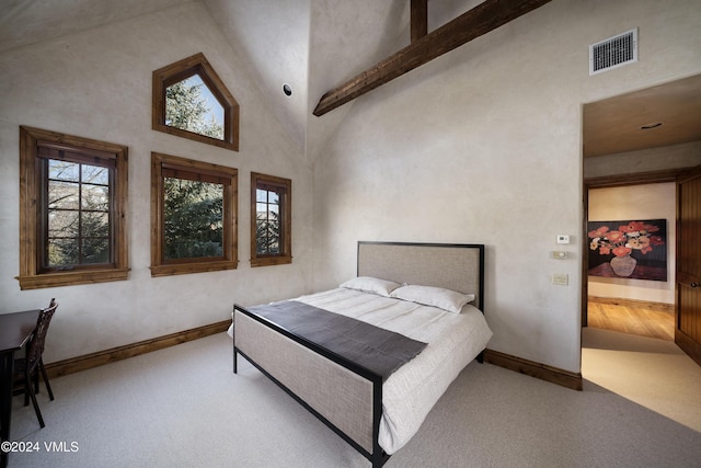 bedroom with beam ceiling, light carpet, and high vaulted ceiling