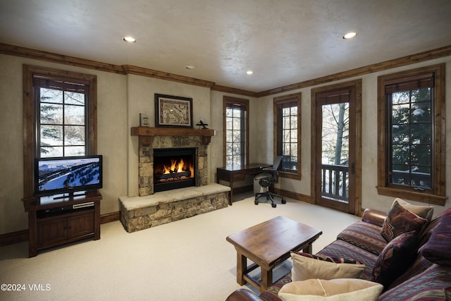 living room with crown molding, a stone fireplace, and carpet floors