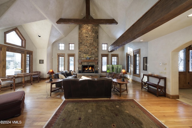 living room featuring high vaulted ceiling, beam ceiling, a fireplace, and light hardwood / wood-style floors