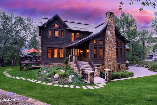 back house at dusk with a deck and a lawn