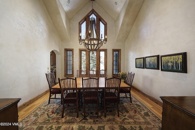 dining area featuring an inviting chandelier, hardwood / wood-style floors, and a high ceiling