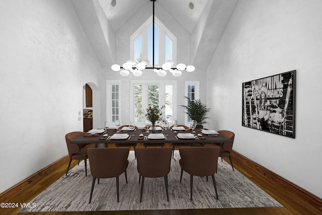 dining space with wood-type flooring, a towering ceiling, and a notable chandelier