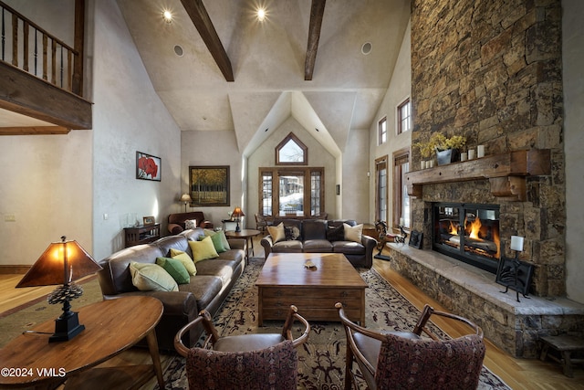 living room featuring beam ceiling, a fireplace, hardwood / wood-style flooring, and a high ceiling