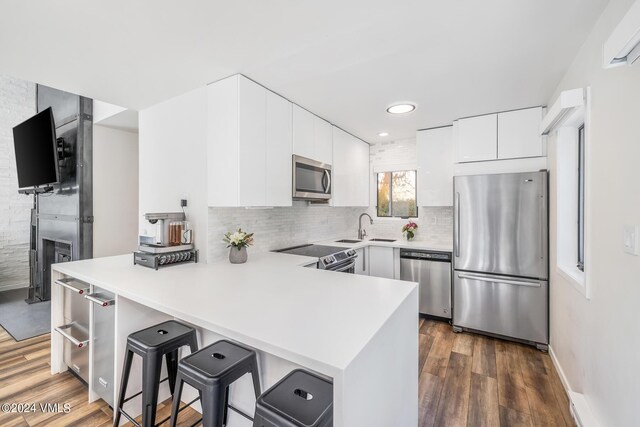 kitchen with a breakfast bar area, tasteful backsplash, kitchen peninsula, stainless steel appliances, and white cabinets