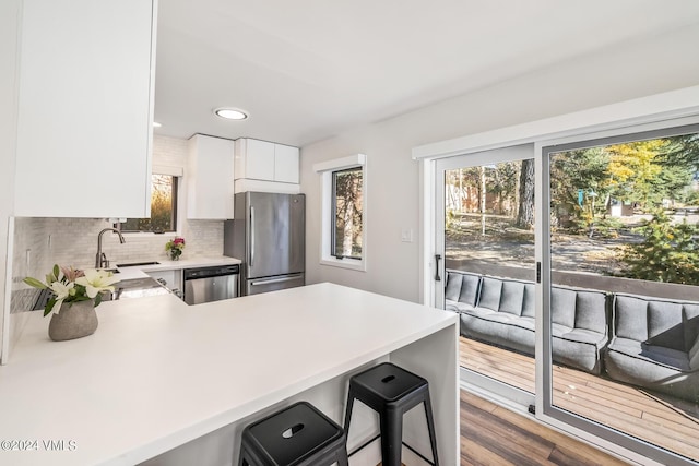 kitchen featuring a breakfast bar area, white cabinetry, appliances with stainless steel finishes, kitchen peninsula, and backsplash