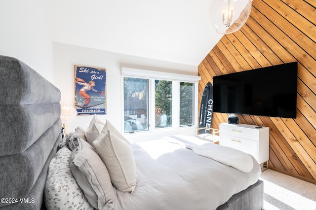 carpeted bedroom featuring lofted ceiling and wood walls