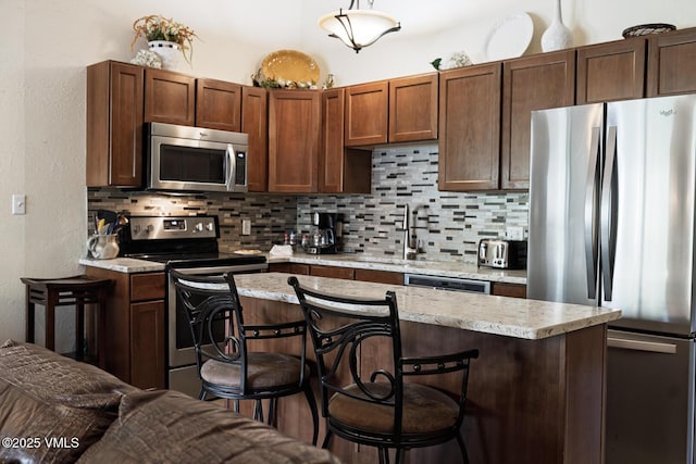 531 E Lionshead Cir Unit 303, Vail, CO 81657 - kitchen with appliances with stainless steel finishes, a sink, a kitchen breakfast bar, decorative backsplash, and a center island