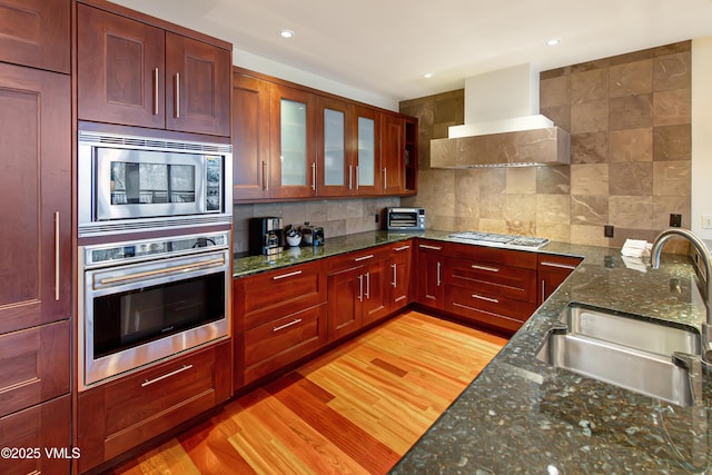 1325 Westhaven Dr Unit A302, Vail, CO 81657 - kitchen featuring stainless steel appliances, wall chimney exhaust hood, backsplash, light wood finished floors, and recessed lighting