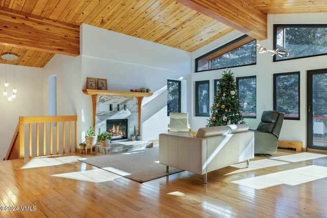 living room with a high end fireplace, beam ceiling, light hardwood / wood-style flooring, and wooden ceiling