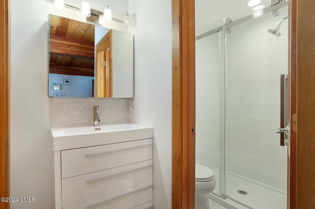 bathroom with vanity, decorative backsplash, toilet, and walk in shower