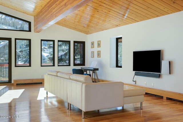 living room featuring plenty of natural light, vaulted ceiling with beams, and light hardwood / wood-style flooring