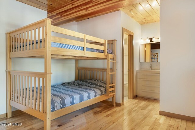 bedroom featuring lofted ceiling, sink, light hardwood / wood-style floors, and wooden ceiling