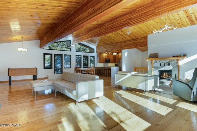 living room featuring wood ceiling, a fireplace, light hardwood / wood-style floors, and lofted ceiling with beams