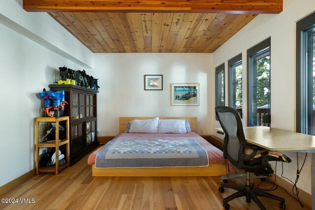 bedroom with beamed ceiling, wooden ceiling, and light hardwood / wood-style floors