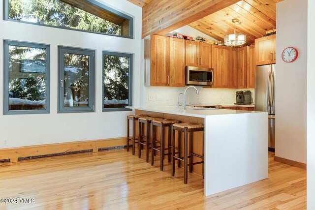 kitchen with pendant lighting, lofted ceiling with beams, sink, kitchen peninsula, and stainless steel appliances