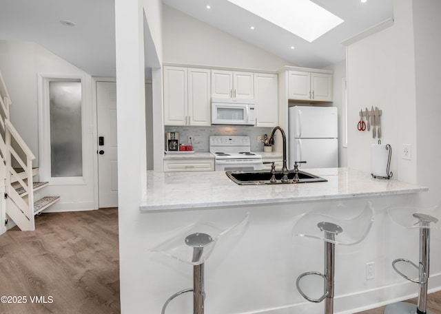 4480 Timber Falls Ct Unit 1507, Vail, CO 81657 - kitchen featuring white appliances, lofted ceiling, a breakfast bar area, a skylight, and a sink
