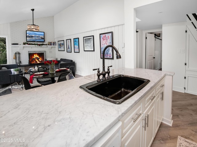 4480 Timber Falls Ct Unit 1507, Vail, CO 81657 - kitchen featuring a sink, lofted ceiling, wood finished floors, a fireplace, and light stone countertops