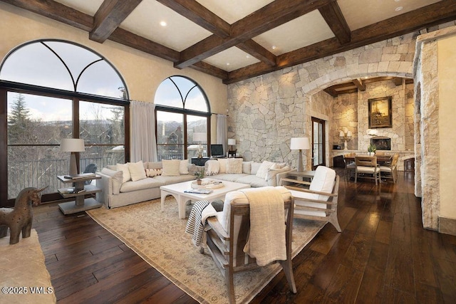 living area with hardwood / wood-style floors, coffered ceiling, a high ceiling, arched walkways, and beamed ceiling