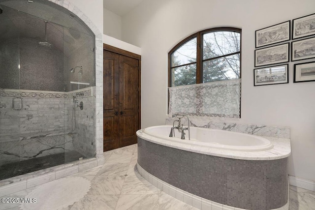 bathroom featuring marble finish floor, a shower stall, and a garden tub