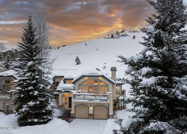 chalet / cabin with a garage, a balcony, and a chimney