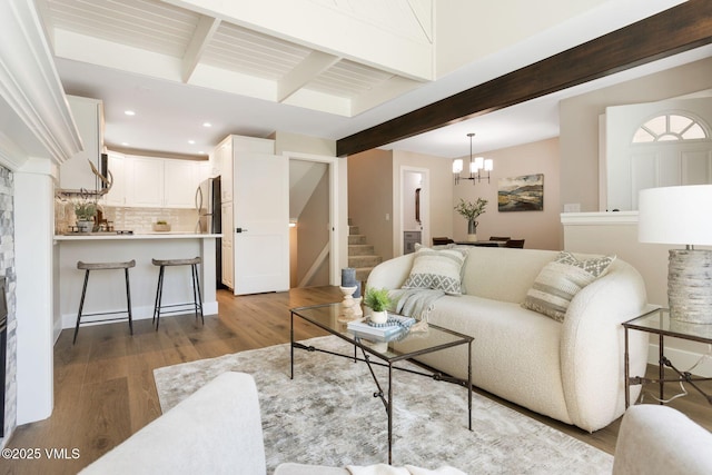 living area with beamed ceiling, an inviting chandelier, recessed lighting, wood finished floors, and stairs