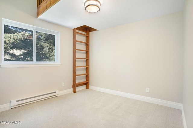 unfurnished room featuring a baseboard heating unit, light colored carpet, and baseboards