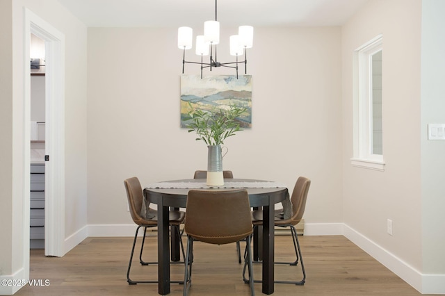 dining room featuring an inviting chandelier, wood finished floors, and baseboards