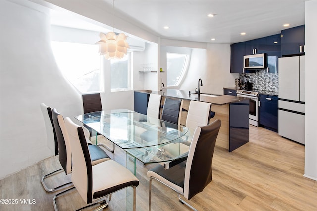 dining room featuring recessed lighting, light wood-style floors, and an AC wall unit