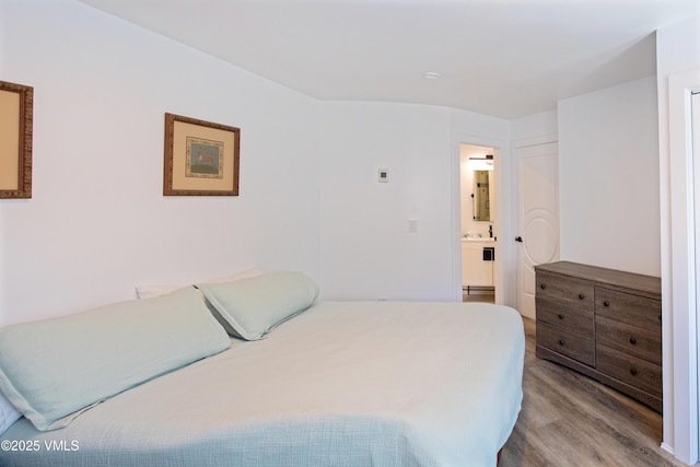 bedroom with connected bathroom and wood finished floors