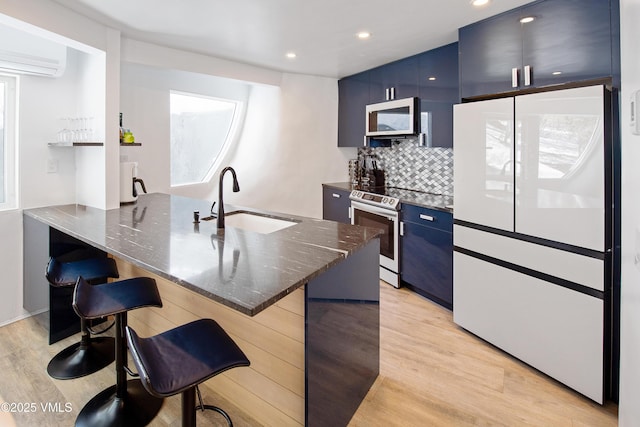 kitchen with white microwave, a breakfast bar area, light wood-style flooring, stainless steel range with electric cooktop, and a sink