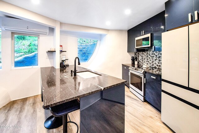 kitchen featuring light wood-style flooring, range with electric stovetop, a wall mounted AC, and a sink