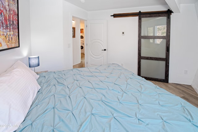 bedroom featuring a barn door and wood finished floors