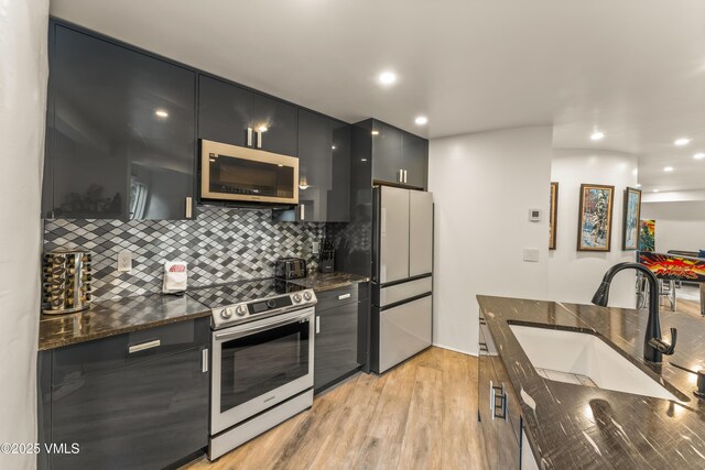 2940 Basingdale Blvd Unit 2, Vail, CO 81657 - kitchen with appliances with stainless steel finishes, a sink, dark cabinets, light wood-style flooring, and tasteful backsplash