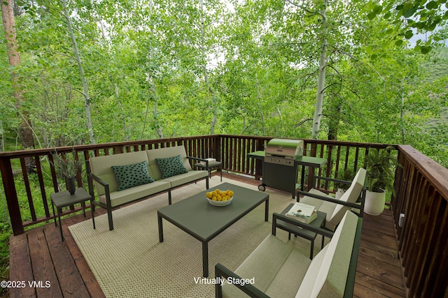 wooden terrace with area for grilling, a wooded view, and outdoor lounge area