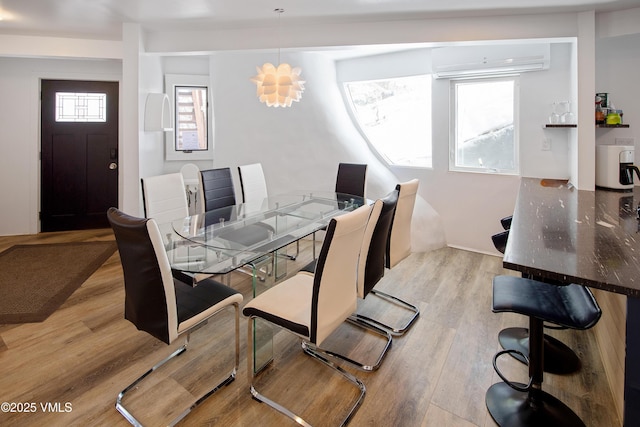 dining room with a wall mounted air conditioner and light wood-style floors