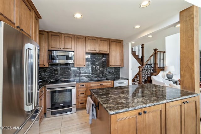 kitchen featuring dark stone counters, stainless steel appliances, decorative backsplash, and brown cabinets